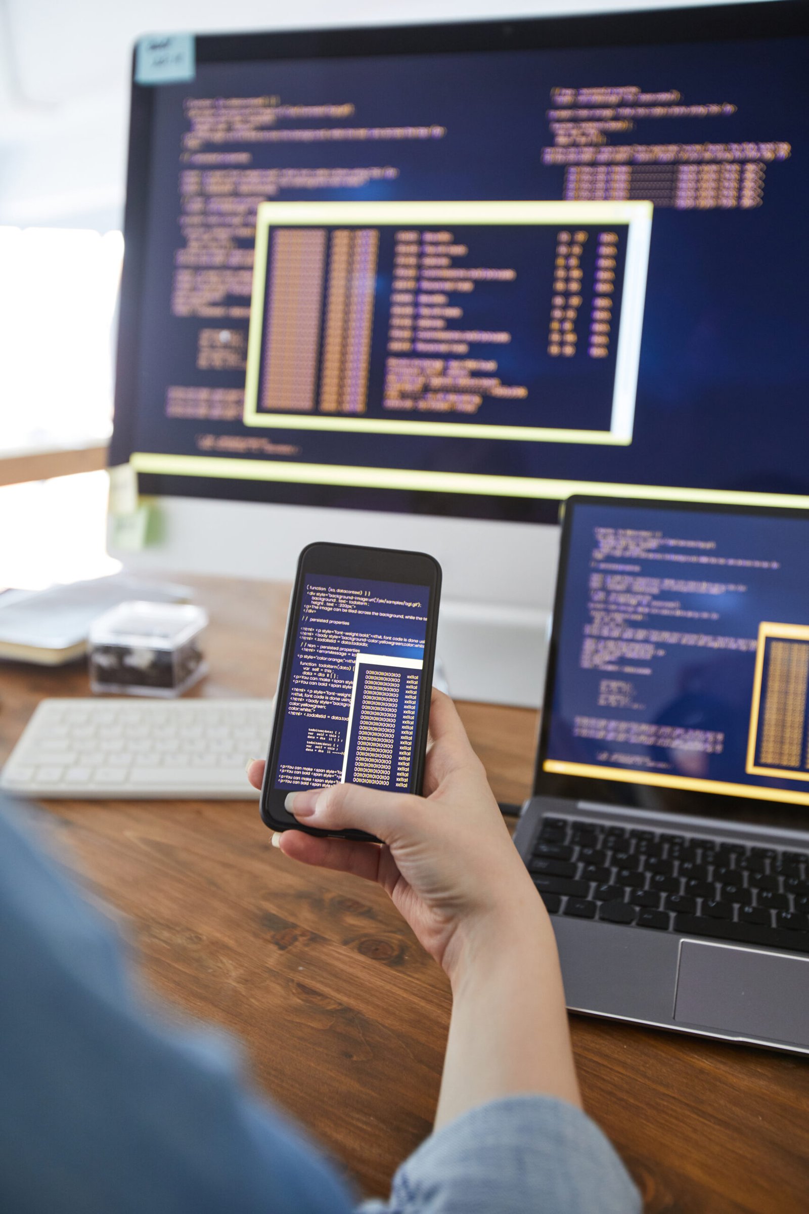 https://rishfotech.com/wp-content/uploads/2025/09/vertical-close-up-female-hand-holding-smartphone-with-code-screen-while-working-desk-office-female-it-developer-concept-copy-space-scaled.jpg
